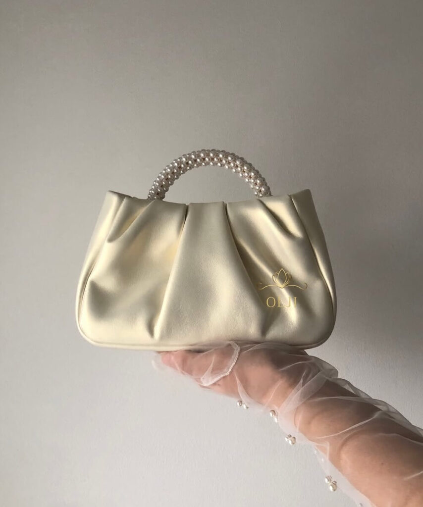 Шкіряна перламутрова сумочка з ручкою з перлин та шкіряним поясом